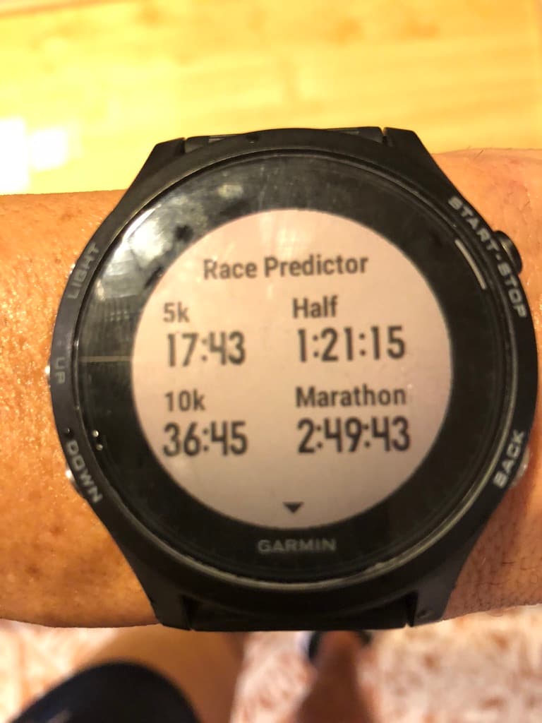 Garmin watch showing a generic Race Predictor screen: 5k 17:43, 10k 36:45, Half 1:21:15, Marathon 2:49:43